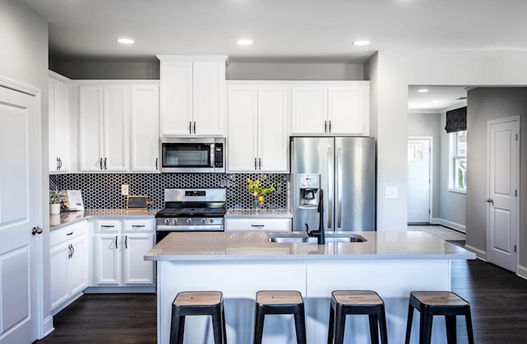 Alexander quick move-in kitchen with beautiful quartz counters, bright white cabinets, and black tile backsplash