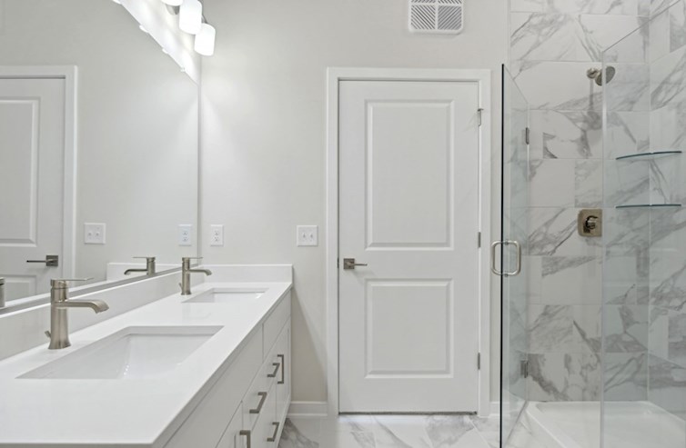 Austin primary bathroom with dual rectangular undermount porcelain sinks, white shaker cabinets, iced white quartz countertops, and walk-in shower with frameless shower enclosure and handset ceramic tile