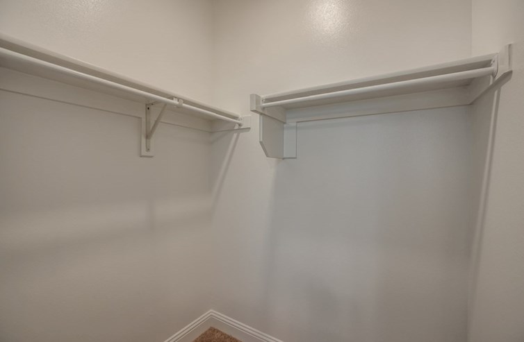 Sherwood primary bedroom walk-in closet with white shelves and carpet