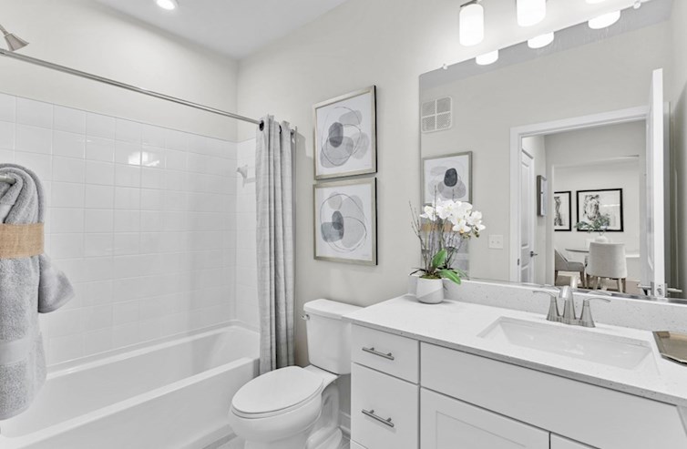 Bradford secondary bathroom with iced white quartz countertops, white cabinets, and a spacious tub/shower with white ceramic tile