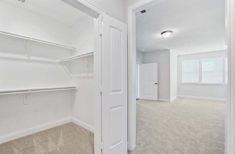 Clifton primary bedroom walk-in closet with white shelves and carpet