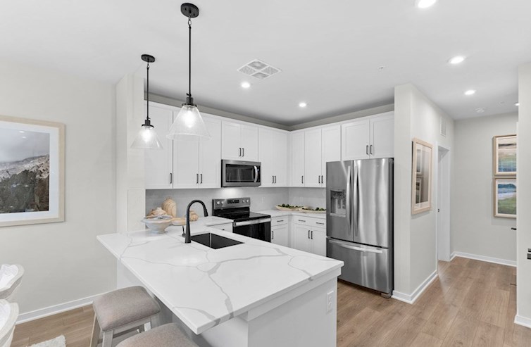 Dogwood eat-in kitchen with 2 stools, 2 pendant lights, white cabinets, calacatta classique quartz countertops, stainless steel appliances, and black hardware