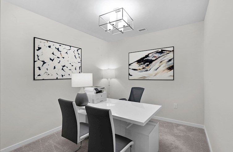 Bradford carpeted office with white table, printer, 2 lamps, wall art, and 3 chairs
