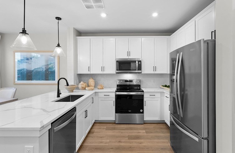 Dogwood eat-in kitchen with pendant lighting, white cabinets, calacatta classique quartz countertops, stainless steel appliances, and black hardware overlooking the breakfast area