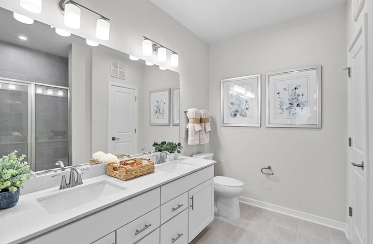 Bradford primary bathroom with linen closet, iced white quartz countertops, and white cabinets