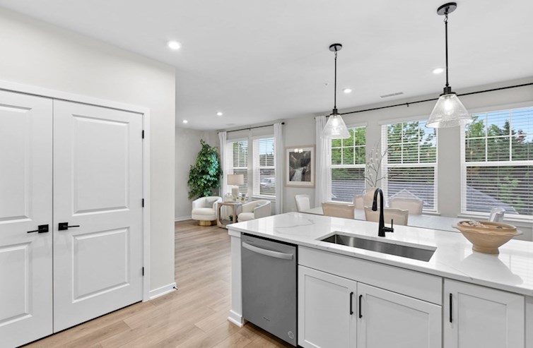 Dogwood eat-in kitchen with pantry, white cabinets, calacatta classique quartz countertops, stainless steel appliances, and black hardware overlooking the breakfast area