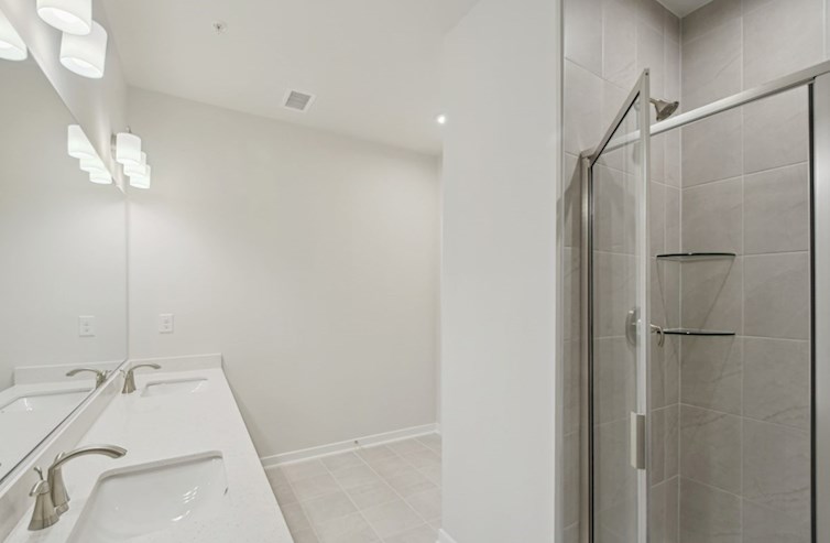 Denmark primary bathroom with white quartz countertops, two rectangular porcelain undermount sinks, white shaker cabinets, and walk-in shower with hand-set ceramic tile