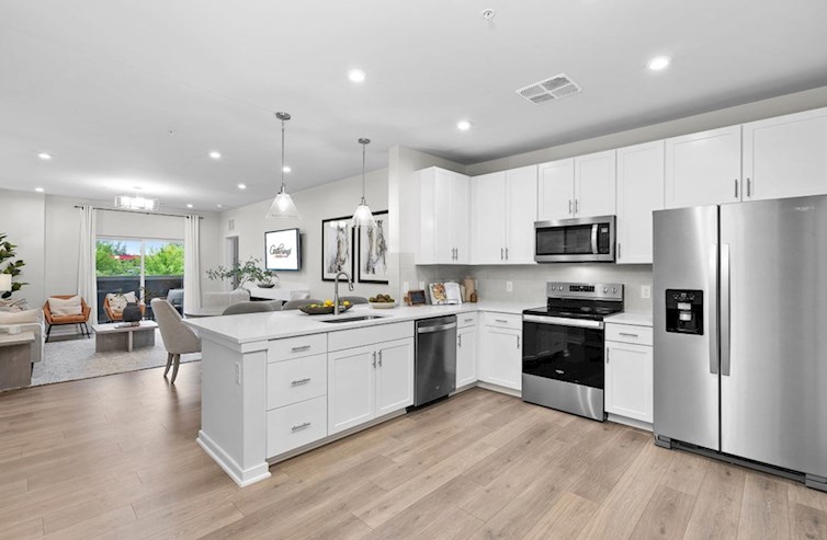 Bradford eat-in kitchen with quartz countertops, white cabinets, stainless steel appliances, wall art, and seating that opens to the dining room and living room