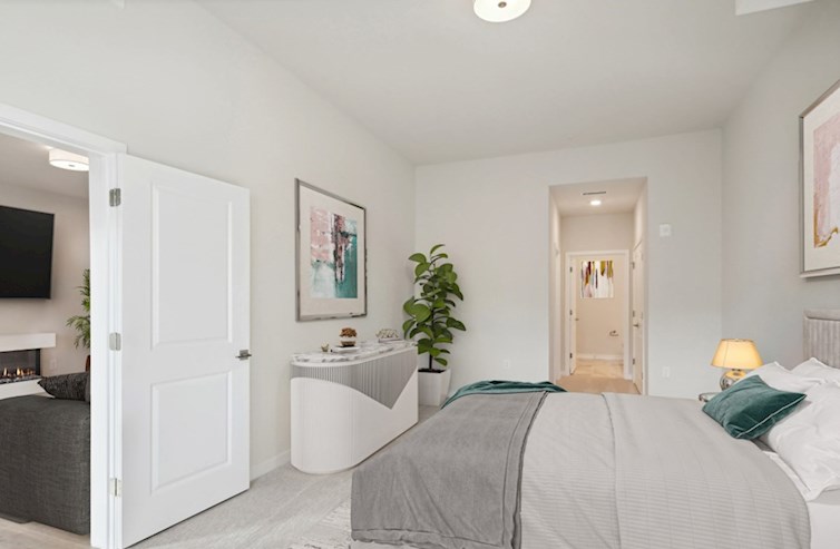 Austin carpeted bedroom featuring extended ceiling, king-size bed, nightstand, dresser, dual walk-in closets, and access to both the primary bathroom and living room