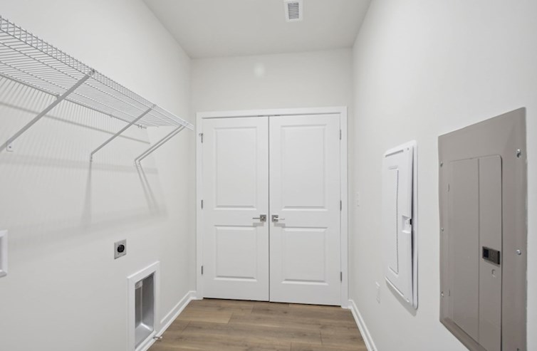 Denmark laundry room with washer & dryer hookups, ventilated shelving, electric panel, media panel, laminate floors, and double doors to water heater and fire alarm system