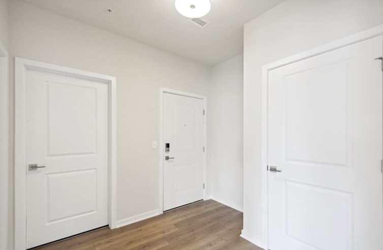 Denmark foyer with laminated floors, ceiling mounted light fixture, and access to front door, coat closet, and secondary bathroom